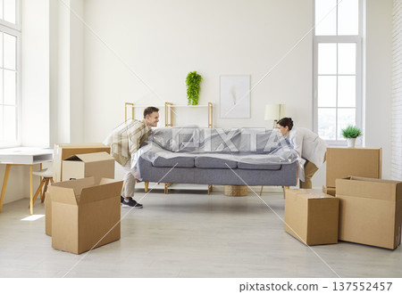 Happy proud man and woman move sofa while moving into new home apartment Happy proud man and woman move sofa while moving into new home apartment 137552457