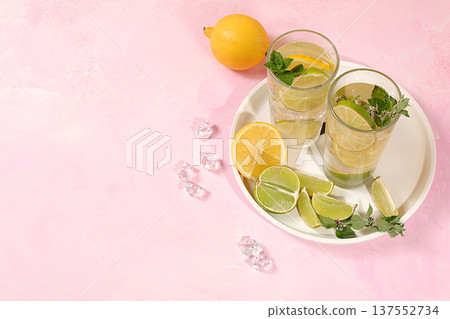 Detox diet and healthy lifestyle concept, Summer drink with lemon, mint, lime and orange on a light table, mojito or cocktail improves metabolism and promotes weight loss, summer party advertisement. Detox diet and healthy lifestyle concept, Summer drink with lemon, mint, lime and orange on a light table, mojito or cocktail improves metabolism and promotes weight loss, summer party advertisement. 137552734