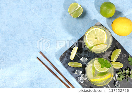 Summer drink with lemon, mint, lime and orange on a light table, mojito or cocktail improves metabolism and promotes weight loss, detox diet and healthy lifestyle concept, summer party advertisement. Summer drink with lemon, mint, lime and orange on a light table, mojito or cocktail improves metabolism and promotes weight loss, detox diet and healthy lifestyle concept, summer party advertisement. 137552736