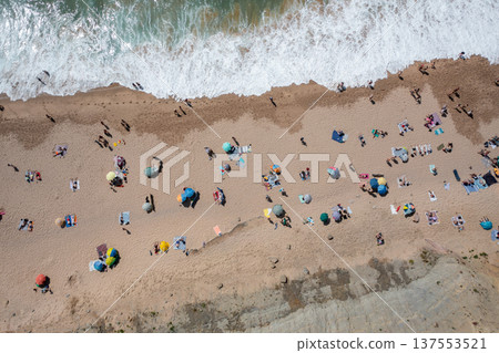 Tourists and colorful parasols on sandy seashore Tourists and colorful parasols on sandy seashore 137553521