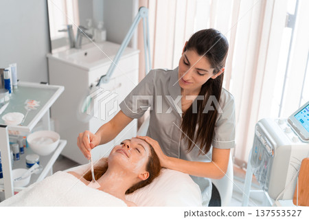 Cosmetologist applying facial mask to woman in Cosmetologist applying facial mask to woman in 137553527