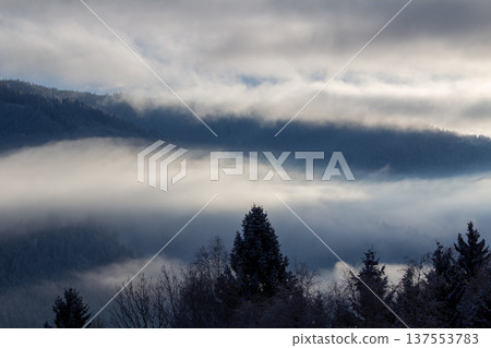 Sunrise makes a breakthrough in the mist between the mountains Sunrise makes a breakthrough in the mist between the mountains 137553783