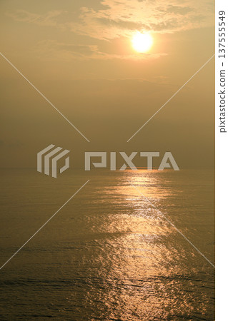 Sun sets over the ocean creating golden reflections on water 137555549