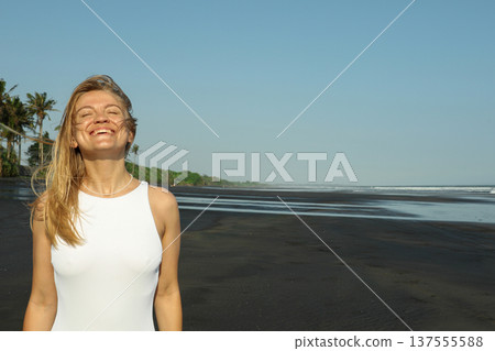 A woman smiles on a black sand beach in Bali 137555588
