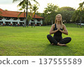 Woman performs yoga on grass near a hotel in Bali 137555589