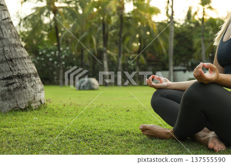 A person practices yoga on the grass surrounded by trees A person practices yoga on the grass surrounded by trees 137555590