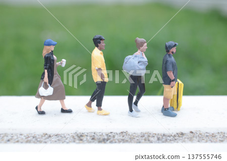 Four Tiny Figures Walking Forward in Neat Formation 137555746