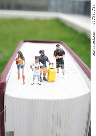 Tiny Figures Stand Together Along Central Book Spine 137555755