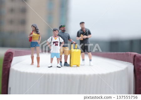Tiny Group Stands Together Atop Thick Hardcover Book 137555756