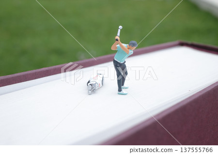 Tiny Figurine Performs Full Golf Swing On Book 137555766