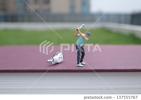 Tiny Figurine Performs Golf Swing On Hardcover Book 137555767