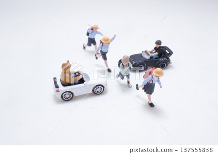 Miniature schoolchildren interacting playfully with small toy cars 137555838