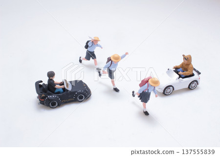Miniature schoolchildren interacting playfully with small toy cars 137555839