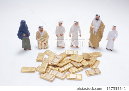 Miniature desert figures surrounding pile of gold bars 137555841