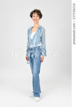 一位五十多歲的女性以模特兒姿勢站立，左腳在前，背景為白色。 137556218