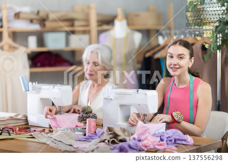 Elderly and adult women seamstresses sewing on machine Elderly and adult women seamstresses sewing on machine 137556298