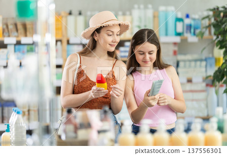 Woman with teen girl are busy choosing sunscreen cream at pharmacy Woman with teen girl are busy choosing sunscreen cream at pharmacy 137556301