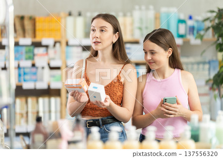 Woman with daughter choosing pills in pharmacy 137556320