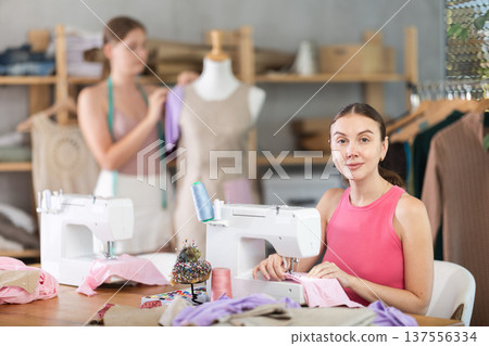 Adult woman sews female assistant working with mannequin Adult woman sews female assistant working with mannequin 137556334