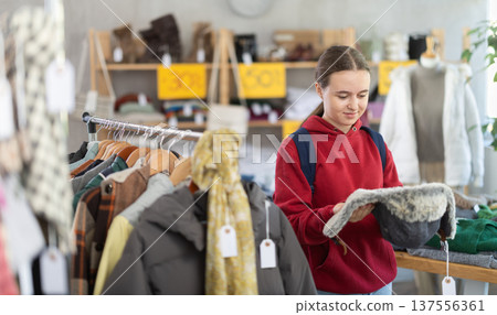 Teenage girl choosing fur hat in clothing store 137556361