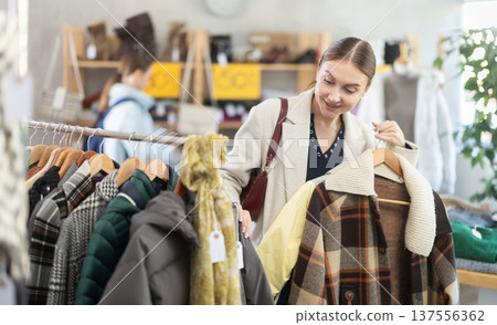 Adult woman chooses plaid jacket in clothing store 137556362