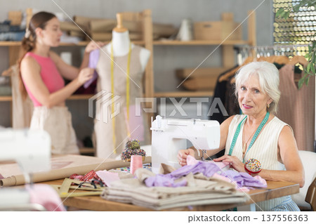 Senior woman tailor busy with sewing machine, female employee work with mannequin 137556363
