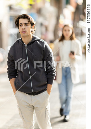 Upset young man walking away from woman on street 137556366