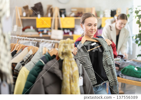 Teenage girl choosing jackets in the store Teenage girl choosing jackets in the store 137556389