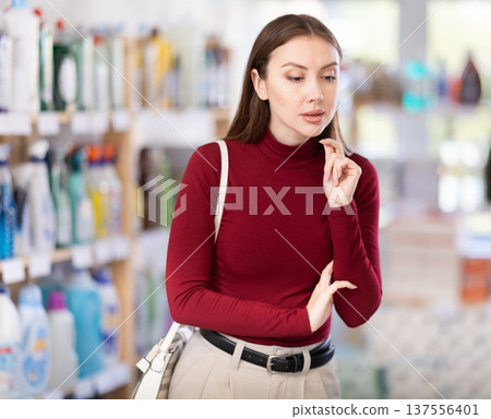 Young woman chooses household chemicals in store Young woman chooses household chemicals in store 137556401