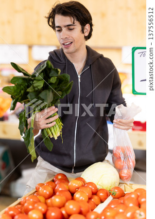 Guy shopping, examine vegetable in store and buy elect spinach Guy shopping, examine vegetable in store and buy elect spinach 137556512