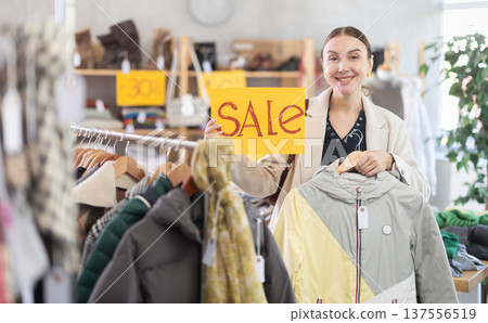 Young woman holding sale sign in store Young woman holding sale sign in store 137556519