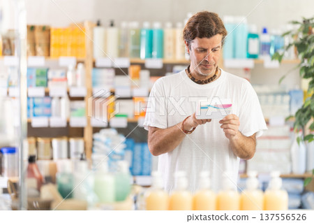 adult man chooses a package of pills in a pharmacy adult man chooses a package of pills in a pharmacy 137556526