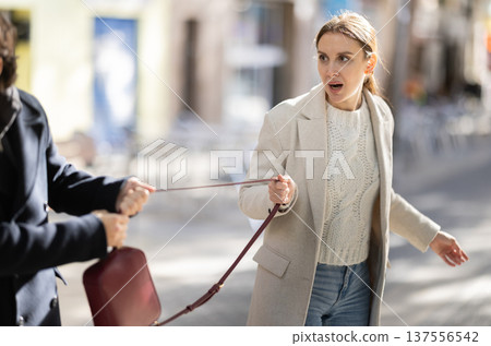 Young man snatching handbag from woman on street 137556542