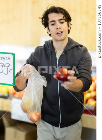 Man chooses apples for purchase in greengrocer shop 137556545