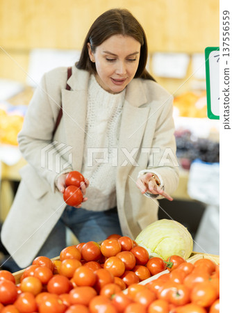 Young woman chooses tomatoes in store Young woman chooses tomatoes in store 137556559