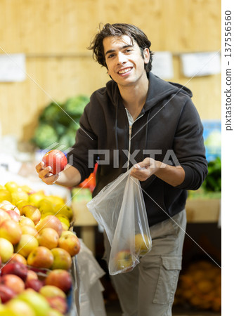 Young man choosing apples in vegetable shop 137556560