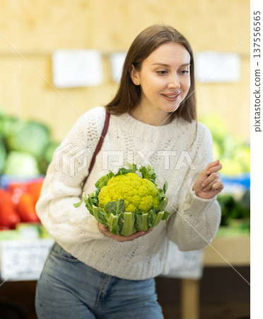 Female shopper selects cauliflower at grocery store 137556565