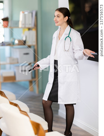 Girl doctor speaker with remote control during lecture Girl doctor speaker with remote control during lecture 137556573