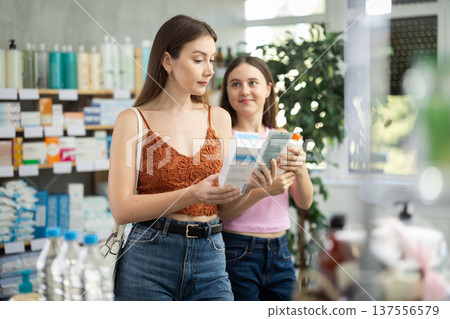 Woman with teen girl are busy choosing atopic cream at pharmacy Woman with teen girl are busy choosing atopic cream at pharmacy 137556579