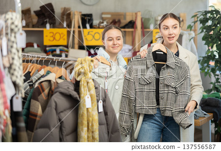 Two focused female clients carefully looking something for autumn-winter season in clothing mall. Family shopping and seasonal Black Friday sales 137556587