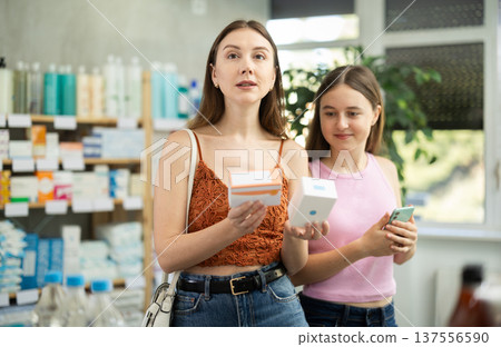 Woman with teen girl are busy choosing tablet pills at pharmacy Woman with teen girl are busy choosing tablet pills at pharmacy 137556590