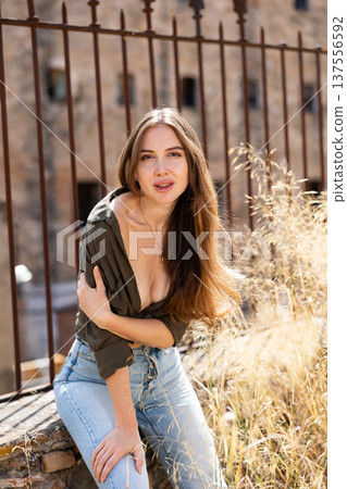 Portrait of sexy blonde woman with puffy hair in shirt and jeans on summer street Portrait of sexy blonde woman with puffy hair in shirt and jeans on summer street 137556592