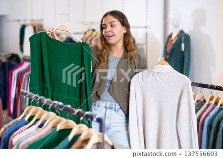Casual young woman chooses summer clothes in clothing store 137556603
