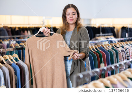Young woman choosing knitted sweater in store Young woman choosing knitted sweater in store 137556626