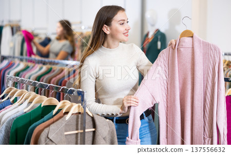 Girl is deciding on turtleneck sweater in women cloths shop Girl is deciding on turtleneck sweater in women cloths shop 137556632