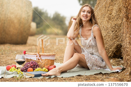 Young woman in dress sits during picnic Young woman in dress sits during picnic 137556670