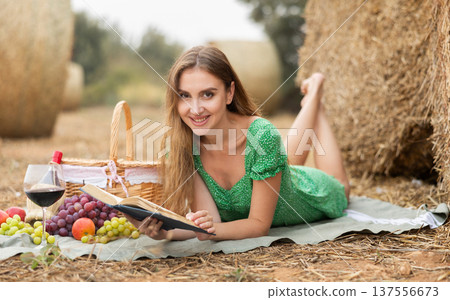Woman in dress lying reading book during picnic 137556673