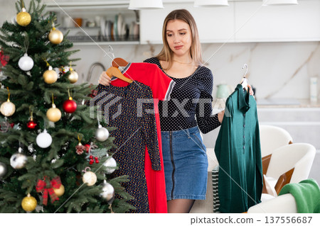 Upset woman not happy with her old dresses in wardrobe for Christmas celebration in apartment 137556687