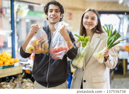 Young couple picking fresh fruits and vegetables at market 137556736