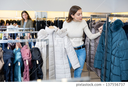 Female purchaser choosing winter down jacket in shopping center 137556737